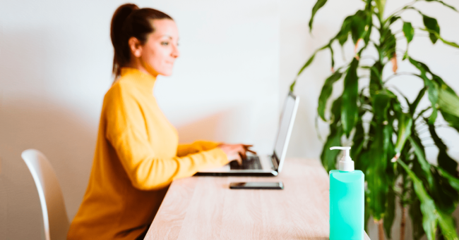 mujer trabajando en oficina limpia con productos de limpieza en su escritorio