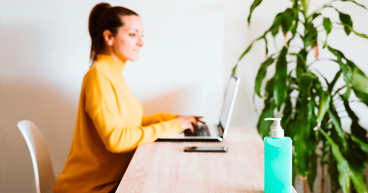 mujer trabajando en oficina limpia con productos de limpieza en su escritorio
